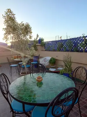 a glass table and chairs on a patio at Riad Zahri 18 in Marrakech