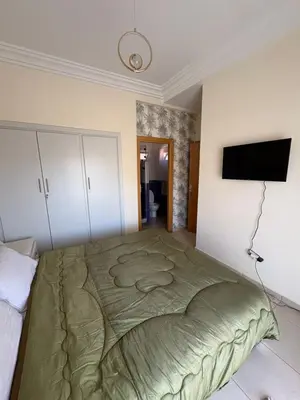 a bedroom with a large bed and a flat screen tv at Les Amandiers in Marrakech