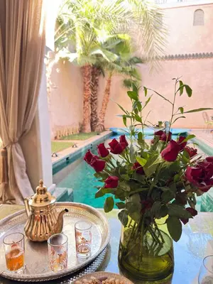 a vase of roses on a table next to a pool at Riad 29 Mouassine in Marrakech