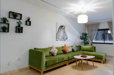a living room with a green couch and a table at Gueliz BEST Residence Nour!! 3 Bedrooms Large Modern Apartment, walking distance to train station and everything in Marrakech