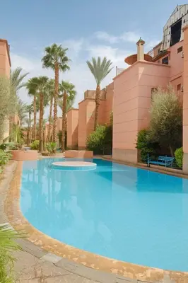 a large blue swimming pool with palm trees at Riad Mounad with pool - close to Jemaa el-fna in Marrakech