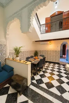 a restaurant with a table and chairs and a checkerboard floor at Riad Mounad with pool - close to Jemaa el-fna in Marrakech