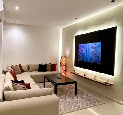 a living room with a couch and a tv on a wall at Wonderful & Warm in City Center in Oulad Akkou