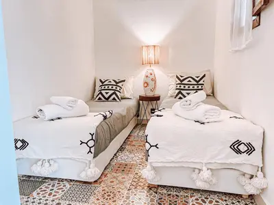 a bedroom with two beds with white sheets and a lamp at Riad Sharif in Marrakech