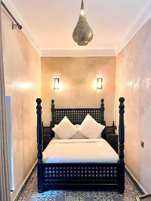 a bedroom with a black bed with white pillows at Hotel Jannat in Marrakech