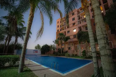 a swimming pool in front of a building with palm trees at œil de la vallée in Marrakech