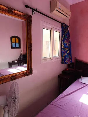 a bedroom with a mirror and a bed and a window at Riad kech residence al Qarya syahiya Marrakech in Marrakech