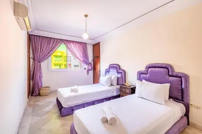 two beds in a room with purple furniture at Cosy Appartement Rue Loubnane in Marrakech