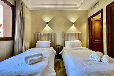 two beds in a room with white sheets and pillows at Al Qantara with Terrace and Pool in Marrakech