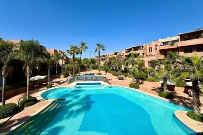 a large swimming pool with palm trees and a building at Al Qantara with Terrace and Pool in Marrakech