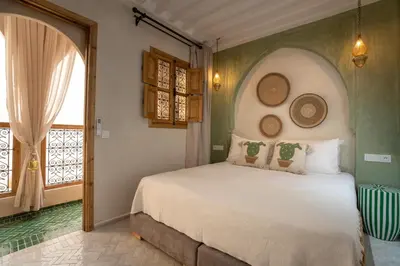a bedroom with a white bed with an arched window at Riad Tassili Vert in Marrakech