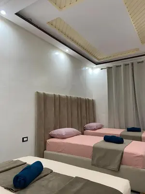 a room with three beds with pink and purple pillows at KSYI IMMO 6 Marrakech Aéroport in Marrakech