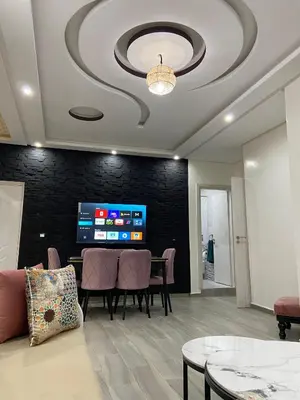 a living room with a table and chairs and a tv at KSYI IMMO 6 Marrakech Aéroport in Marrakech