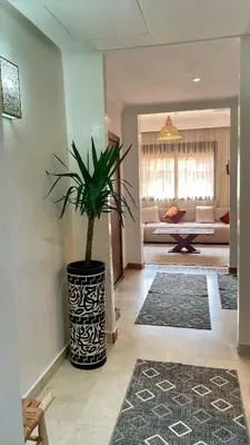 a living room with a potted plant on the floor at Premium Village, appartement cosy in Marrakech