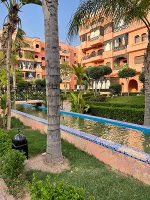a resort with a swimming pool in front of a building at Premium Village, appartement cosy in Marrakech