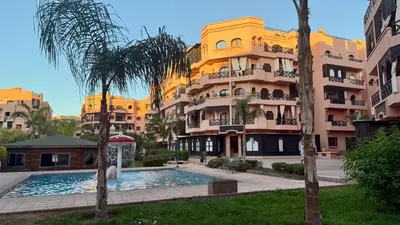 a large apartment building with a swimming pool and palm trees at Premium Village, appartement cosy in Marrakech