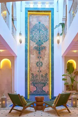 a wall mural in a lobby with two green chairs at Taj Riad Zitoune in Marrakech