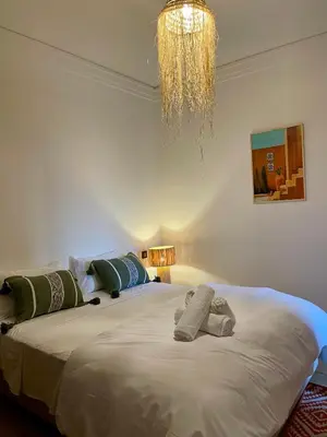 a bedroom with a large bed with pillows and a chandelier at Cozy apartment with pool Downtown Marrakech in Marrakech