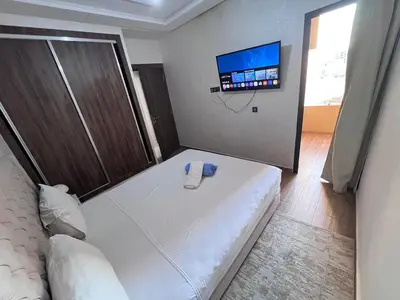 a bedroom with a bed and a flat screen tv at Appartement chic & elegant in Marrakech