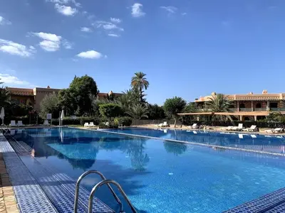 a large swimming pool with chairs in a resort at Sunny apartment in Palmeraie with Pools and Gardens in Marrakech