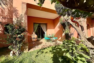 an orange house with a table and a vase in the yard at Sunny apartment in Palmeraie with Pools and Gardens in Marrakech