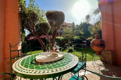 a patio table with a fountain in a garden at Sunny apartment in Palmeraie with Pools and Gardens in Marrakech