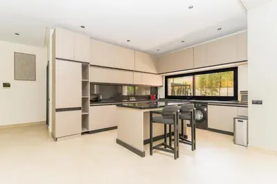 a kitchen with white cabinets and a table and chairs at Villa NAYA in Marrakech