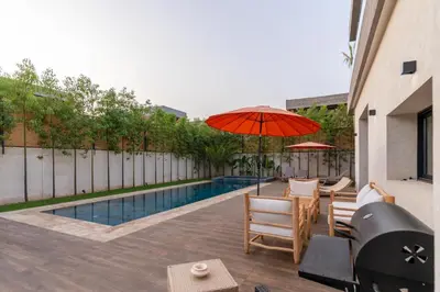 a patio with a table and an umbrella and a pool at Villa NAYA in Marrakech