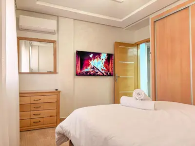a bedroom with a bed and a tv on the wall at Central Apartment in Gueliz Steps from Carré Eden in Marrakech