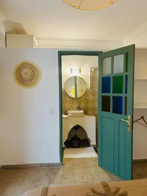 a bathroom with a green door and a mirror at Riad Hami in Marrakech
