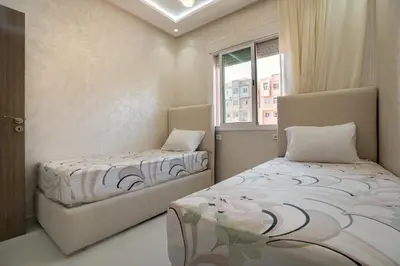 a bedroom with two beds and a window at Titrit Apartment Marrakech in Marrakech
