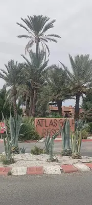 a sign in front of palm trees in a street at Atlas Golf Resort - Marrakech palmeraie a 6 k m du centre in El Mgassem
