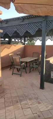a table and chairs under an umbrella on a patio at Atlas Golf Resort - Marrakech palmeraie a 6 k m du centre in El Mgassem
