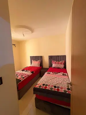 two beds in a small room with red sheets at Appartement 85m dans un quartier calme in Marrakech