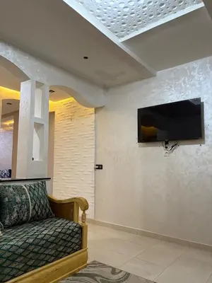 a living room with a couch and a tv on a wall at Appartement 85m dans un quartier calme in Marrakech