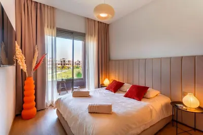 a bedroom with a large bed and a large window at Appartement de charme vue piscine et espace vert in Marrakech