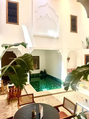 a pool in a room with a table and chairs at Riad RK Suites & Spa in Marrakech