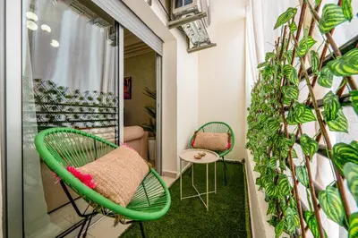 a balcony with a green chair and a plant at Cozy apartment, 2 bedrooms, 10 min from airport and Medina in Marrakech