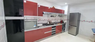 a kitchen with red cabinets and a refrigerator at Apartment Majdoline in Marrakech