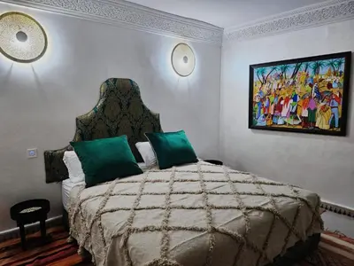 a bedroom with a bed with a painting on the wall at Riad Dar Lghizlane in Marrakech