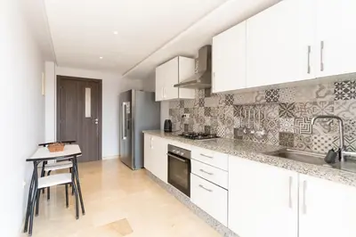 a kitchen with white cabinets and a table in it at Beautiful accommodation with 2 pools & fast WiFi in Marrakech