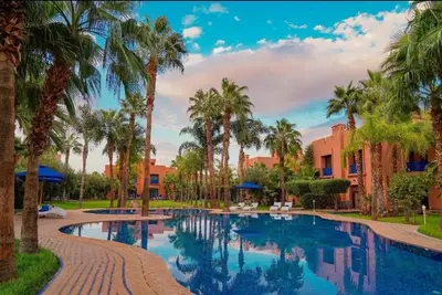 a swimming pool with palm trees and buildings at Villa Premium Marrakech in Marrakech