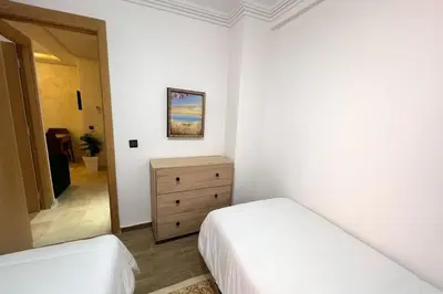 a bedroom with two beds and a dresser and a mirror at NS 53 by KMREI Properties in Marrakech