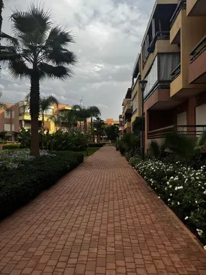 a brick pathway with a palm tree and buildings at Garden level & pool, cozy apartment queen size bed in Marrakech