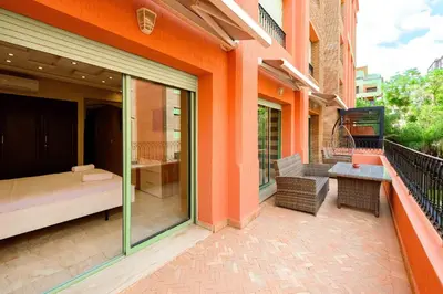 a balcony of a building with a bed and a table at Appartement Confort - Hivernage - Piscine in Marrakech