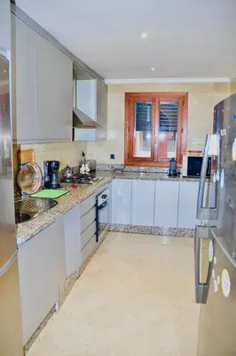 a kitchen with white cabinets and marble counter tops at Appartement Ihssane Plaza Kech in Marrakech