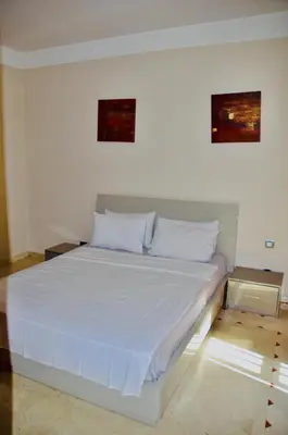 a bed with white sheets and pillows in a room at Appartement Ihssane Plaza Kech in Marrakech