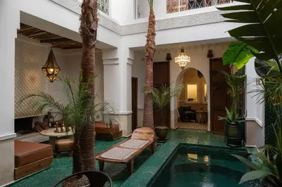 a hotel lobby with a pool and palm trees at Riad Mint - Luxury Oasis in the Medina with Pool in Marrakech