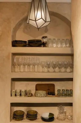 a shelf filled with glasses and plates and a light fixture at Riad Mint - Luxury Oasis in the Medina with Pool in Marrakech