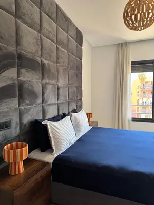 a bedroom with a blue bed with a stone wall at Marrakech Palm View in Marrakech